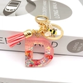 Macro shot of pink resin letter D keychain with golden bee charm and leather tassel - Letter D Bee Keychain