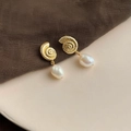 Detail of gold spiral shell earrings with baroque pearls on a ceramic display - Style 22