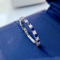 Macro shot of silver eternity ring with blue and white gems on blue velvet box - Dark Blue