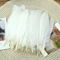 Flat lay of natural white goose feathers on a woven mat for DIY craft and decor - Stiff White (50Pcs)