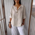 Detail of loose-fit V-neck cotton linen shirt with button and rolled sleeves texture - Apricot