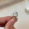 Detailed view of silver open ring with zircons and pearls held by a hand - Silver