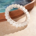 Nahaufnahme eines weißen Jaspis-Perlenarmbands auf einem dekorativen Holztablett - 8mm / Weiß