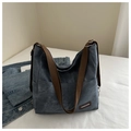 Macro della trama della borsa in denim blu con etichetta in pelle su un letto bianco puro - Blu