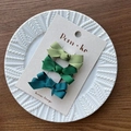 Three green grosgrain ribbon bow hair clips on a beige card in a white ceramic dish - Dark Green Series