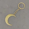 Detailansicht eines Vintage-Bronze-Halbmond-Schlüsselanhängers auf grauem Hintergrund - Antike Bronze Mond