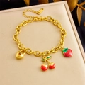 Primer plano de pulsera dorada con dijes de cereza, fresa y candado de corazón - Estilo De Colgante De Cerradura De Corazón Cereza Fresa (B1650)