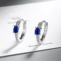 Primer plano de aretes de aro plateados con gemas azules ovales y detalles de circonita - Circonita Azul Real