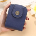 Deep blue Saffiano leather mini makeup pouch with a gold sunflower clasp held in hand - Blue