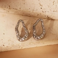 Macro detail of silver fluid lava heart earrings on natural stone surface background - Fluid Abstract Lava Style