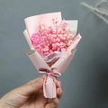 Close-up of a hand holding a mini pink dried baby's breath flower bouquet with a ribbon - Pink Gypsophila (Pink Wrapping)