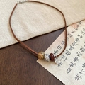 Dettaglio macro di una collana vintage con perline in legno e un ciondolo in argento martellato - Collana-Caffè