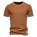 Macro-opname van de bruine wafelgebreide textuur en premium stiksels op het T-shirt met korte mouwen - S / Aardgeel