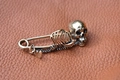 Macro detail of vintage punk skull safety pin brooch in antique bronze on leather surface - Antique Bronze