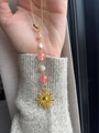 Dettaglio di un ciondolo a sole dorato con perline colorate su un maglione grigio - Ciondolo Sole con Perline Miste Rosa Bianco