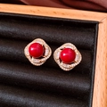 Gros plan détaillé d'une boucle d'oreille en perle rouge et zircon sur velours noir - Rouge