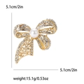 Elegant gold bow brooch with sparkling rhinestones and a large pearl on white background - Gold
