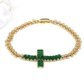 Macro detail of gold cross bracelet with emerald green zircon inlay and lobster clasp - Green