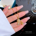 Collier pendentif oiseau doré avec pierres précieuses et zircons blancs tenu en main - Pendentif En Cuivre Et Chaîne En Acier Titane E302