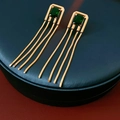Close-up of vintage gold earrings with green square zircon and long chain tassels - Gold With Emerald Gemstone