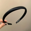 Detailed close-up of a black satin headband featuring a handmade inner label and texture - Black