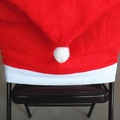Red Santa hat chair cover with white plush trim and pompom on a black folding chair - Non-Woven Santa Hat Chair Cover / 60x50cm