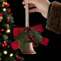 Detail of Christmas bell ornament with red bow, pine branch and berries on blurry tree - Antique Bronze