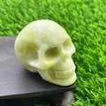 Green natural gemstone crystal skull sculpture with smooth polished finish on wood base - Xiu Jade