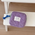 Detail of purple plaid quilted storage bag with a blue rope zipper pull on wooden steps - Purple