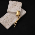 Detailopname van elegante gouden tulpenbroche met gepolijste metalen afwerking op steen - Goud