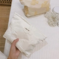 Close-up of white jacquard makeup bag featuring relief butterfly patterns and cloth label - Milky White
