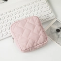 Gros plan d'une trousse à maquillage rose matelassée avec fermeture éclair argentée - Rose Clair
