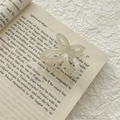 Detail of frosted translucent acetic acid butterfly hair claw clip on an open book - AB White