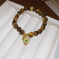Detailed close-up of tiger eye bead bracelet featuring a gold gourd charm with green gem - Gold Coffee (Hulu Style)