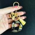 Detail of Letter D resin keychain with real dried flowers, gold bee charm and yellow tassel - Letter D
