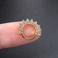 Close-up of a golden piercing ring encrusted with micro-paved zircons held on a finger - Gold Sunburst Hoop