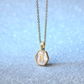 Gold hexagon shell necklace with letter N pendant on a sparkling blue background - Letter N