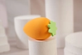 Carrot-shaped orange makeup sponge puff with green leaf detail on a white display stand - Green Carrot
