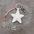 Close-up of a white star-shaped leather keychain with colorful silk ribbon and metal ring - Off White