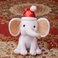 Cute white stuffed elephant plush toy wearing a red Christmas hat in a sitting pose - Christmas Red Hat/White Elephant