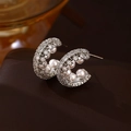 Primer plano de pendientes C plateados con circonitas y perlas blancas sobre cuero - Plata (Pin de plata)