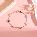 Gold evil eye charm bracelet with seven multicolor beads on a light pink background - Gold Color Anklet