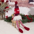 Detail of a Christmas gnome on a wooden bench with snowy pine branches and red berries - Long Leg Doll / Red
