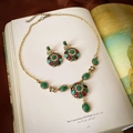Vintage gold-finish jewelry set with colorful gemstones and pearls on an art book - Bronze Gemstone Necklace and Earrings Set