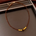 Detail of beaded necklace featuring tiger eye stone center and gold lobster clasp - Necklace-Brown-Yellow