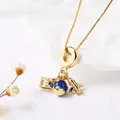 Golden travel necklace with camera, blue globe, and airplane charms on a box chain - Globe Camera (Style D)