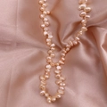 Macro shot of natural champagne baroque freshwater pearls laid on soft silk fabric - Pink