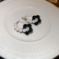 Detailed shot of pearl hoop earrings featuring a polished black floral charm on ceramic - Style 39 Silver Post Earrings - Black Flower