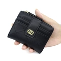 Short black quilted wallet for women with golden buckle held in hand by a model - Black