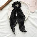 Detail of a black textured fabric hair scrunchie with long ribbons on a ceramic plate - Style with Streamer / Black